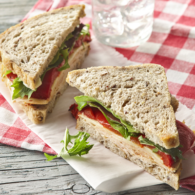 Sandwich poitrine de dinde cuite aux tomates et basilic accompagnée de poivrons rôtis